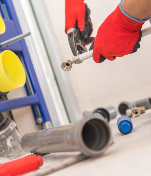 Bathroom and Restroom Plumbing Job. Caucasian Plumber Preparing Water Flashing Pipeline for Toilet Bowl.